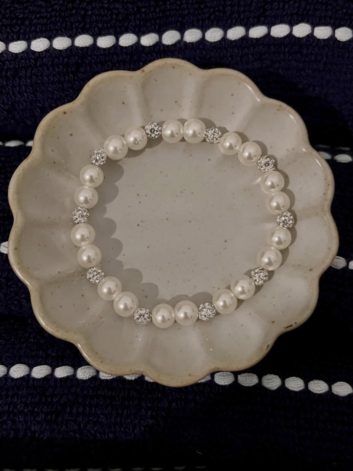 Sol Project: a white plate with a pearl bracelet on it.
