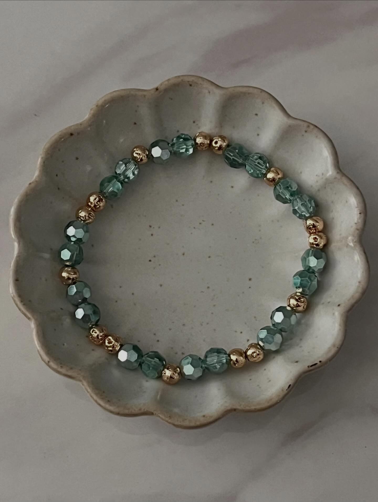 Sol Project: a white plate with a green beaded bracelet on it.